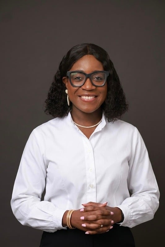 Priscillar Banda McMillan, Virtual Assistant and Business Systems Specialist, in a white shirt against a dark backdrop